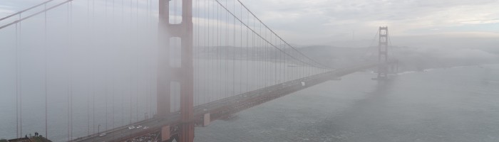 A view of the Golden Gate bridge from the northern edge. Sutro tower can be barely seen in the background. Fog covers much of the frame.
